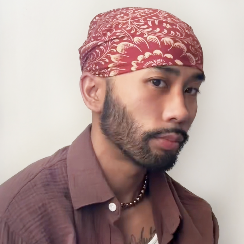 Man wearing a red patterned headscarf against a plain background